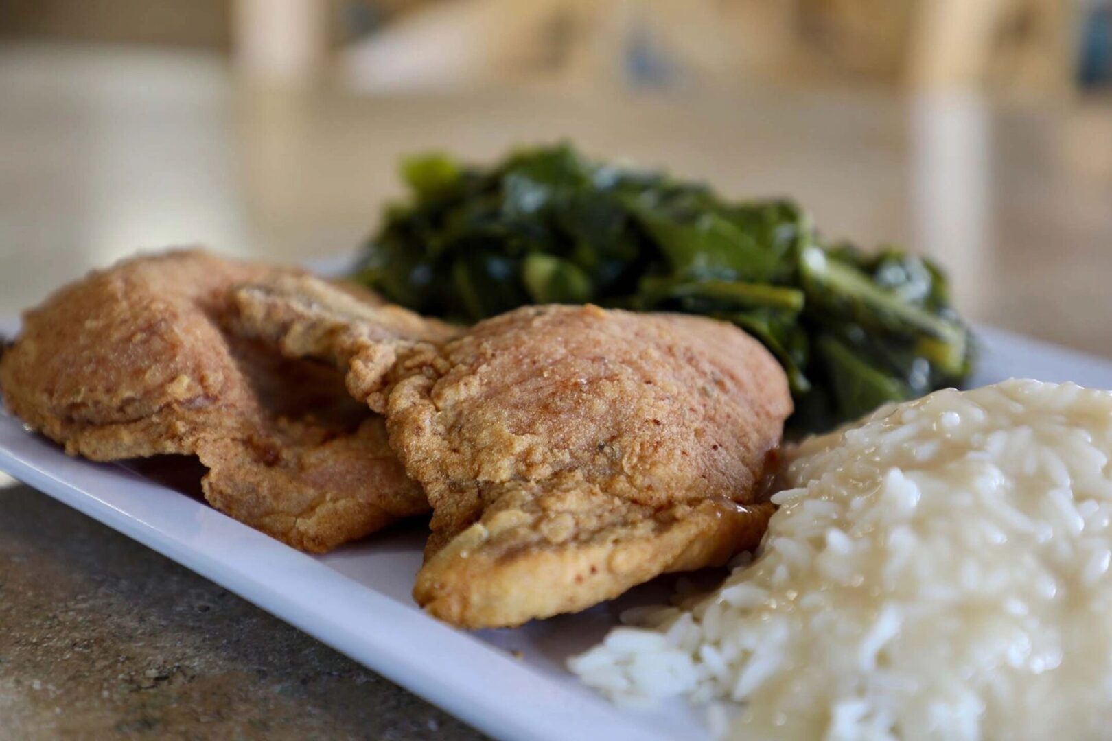 A plate of food with meat, rice and greens.